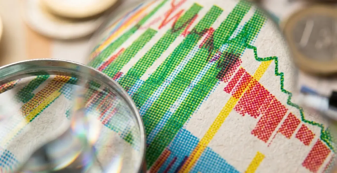 Gros plan sur des graphiques financiers imprimés, avec une loupe créant un effet de bokeh, symbolisant l'analyse détaillée de la rentabilité au-delà des chiffres de surface.