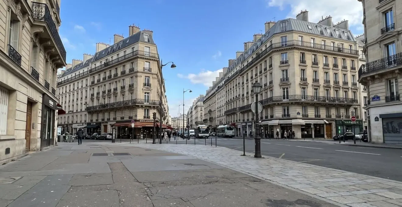 Rue urbaine européenne contemporaine avec architecture haussmannienne, trottoir au premier plan, ciel dégagé, lumière naturelle d'après-midi